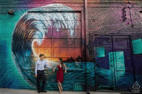 En Rino, Denver, una pareja de Colorado apoyada contra la pintura mural de olas en una pared urbana de la ciudad
