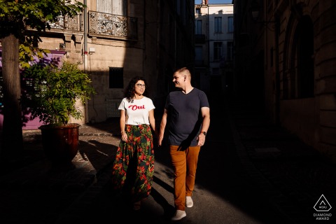 Photo of a couple in Montpellier walking and holding hands in the late afternoon sun