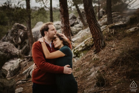 Nella luce dorata del sole che filtra attraverso gli alberi della Forêt de Fontainebleau, una coppia di futuri sposi condivide un tenero e caldo abbraccio durante la sessione di ritratti di fidanzamento.
