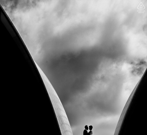 During their engagement portrait session at the Sydney Opera House, the couple stood beneath the arching architecture, with clouds overhead in a minimalist frame of love in Sydney.