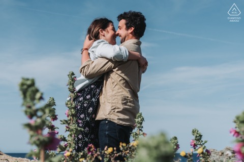 At Île du Petit Gaou in Six-Four-les-Plages, Var, France, the couple shared a passionate embrace, kissing by the flowers under the blue sky, showing their tender and warm love before their upcoming wedding.