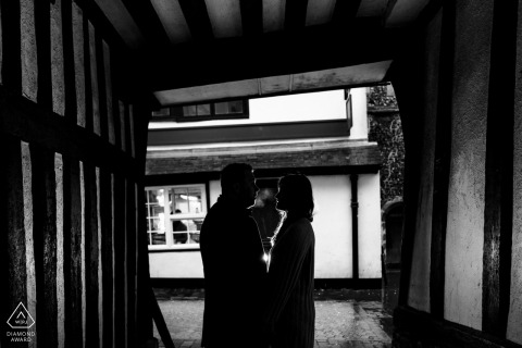 In St Albans city centre, Hertfordshire, the bride & groom-to-be, found refuge in a tudor alley, their silhouettes capturing a romantic scene amidst a sudden downpour during their engagement shoot.