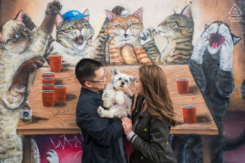 Durante la sessione di ritratti di fidanzamento all'Art District, LA, la coppia si trova di fronte a uno dei murales di gatti del distretto mentre tengono insieme il loro cagnolino bianco, catturando il loro divertimento e l'attesa per il loro imminente matrimonio.
