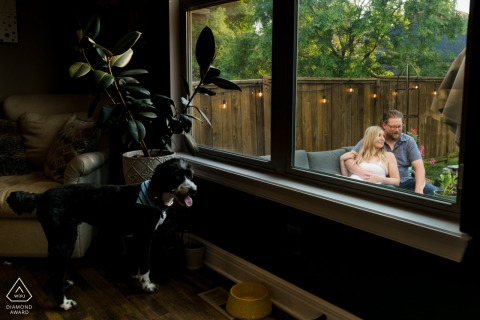A casa della coppia a Kansas City, Missouri, si siedono su una panchina all'aperto nel patio, catturati attraverso la finestra con il loro cane che li guarda amorevolmente.