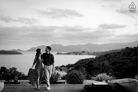 At Samujana Koh Samui, a black and white portrait captures the couple walking along a fancy deck above the water, radiating love and anticipation for their upcoming wedding.