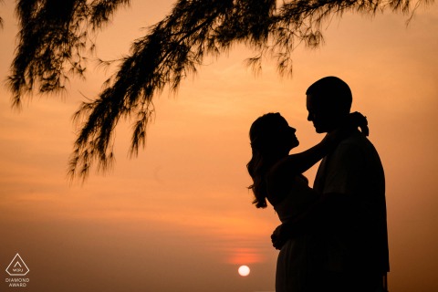 在泰国普吉岛拍摄订婚照时，这对夫妇的剪影沐浴在夕阳的温暖橙色色调中，捕捉着他们准备结婚时的爱情。