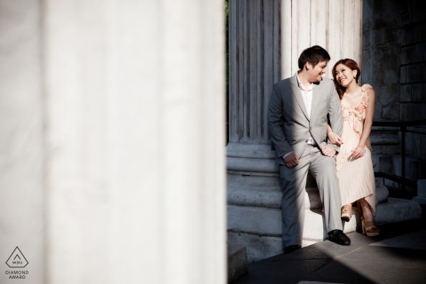 Am oberen Ende einer Treppe in der Nähe massiver Steinsäulen der alten Welt posierte ein Paar in London, Großbritannien, im Sonnenschein für ihr Verlobungsporträt vor ihrer bevorstehenden Hochzeit.