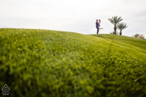 这张照片展示了一对相爱的男人和女人，在亚利桑那州山影连绵起伏的绿色山丘上跳舞，拍摄结婚前的订婚照。