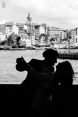 At the Galata Bridge in Turkey, a couple in love poses for pictures, dancing with the striking view of the Galata Tower behind them.