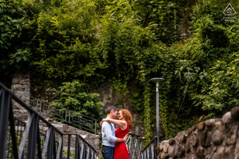 在意大利乌迪内的奇维达莱德尔弗留利，一对情侣在大自然中微笑拥抱，在低矮的石墙前拍摄肖像照。