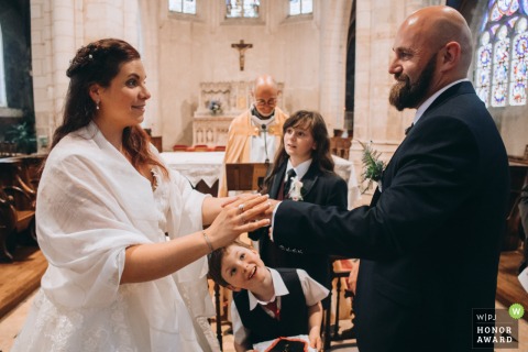At the Aubigny-sur-Ner Church, the bride and groom are holding hands during their church ceremony