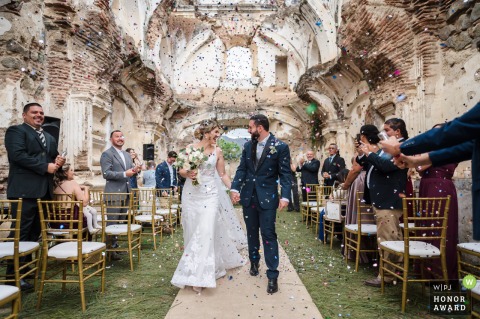 At La Casa de la Ruina, Santa Rosa, Antigua, Guatemala, the bride and groom laugh while exiting the ceremony surrounded by confetti 