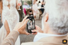 Uno splendido scatto che ritrae un ospite mentre scatta con il cellulare una foto dell'elegante sposa il giorno del suo matrimonio a Borgo Fregnano a Faenza, Italia.