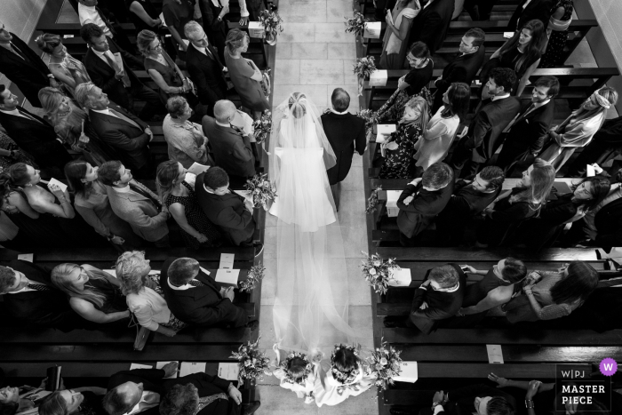 Lucht huwelijksfoto van de bruid en haar vader die onderaan de kerkdoorgang in Zwitserland lopen